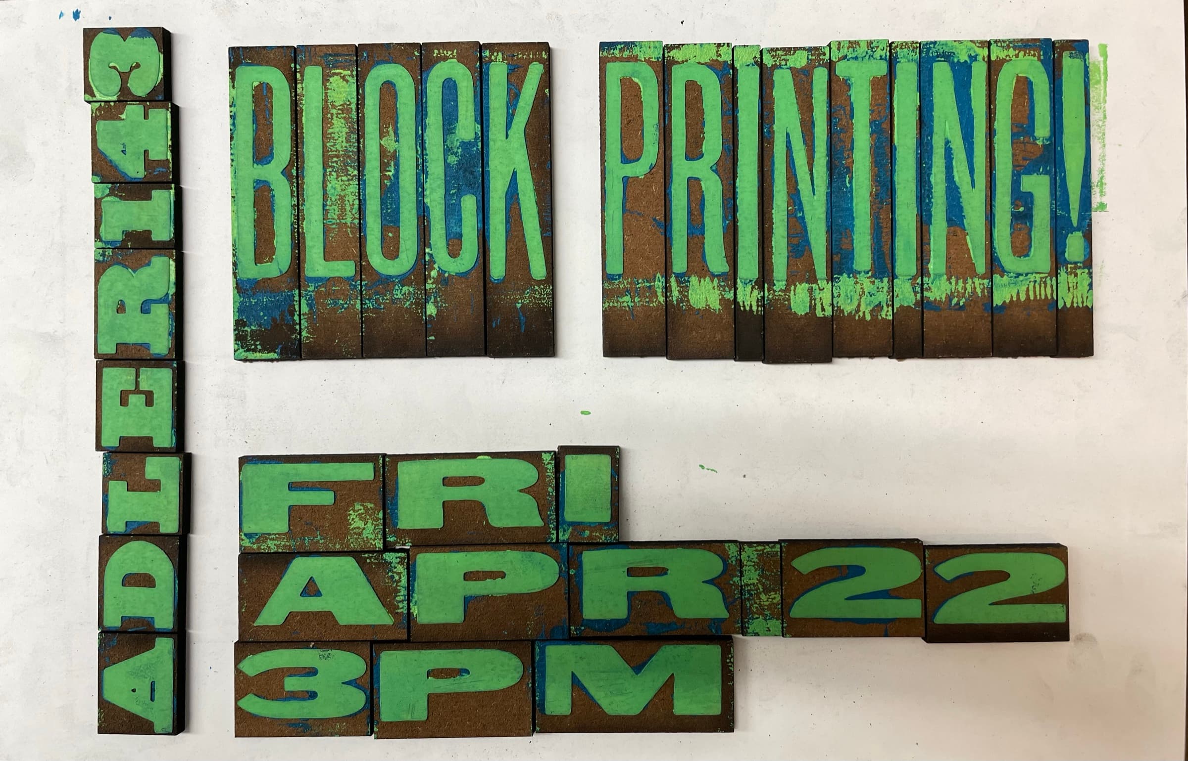 A wooden tray of hand-carved letterpress-style letter blocks set in mirror image: the carved face shows EXCEPT TRABMM (mirrored) and other partial words. The blocks sit in a custom wood tray on a black cutting mat with a brayer roller laid across the top edge.