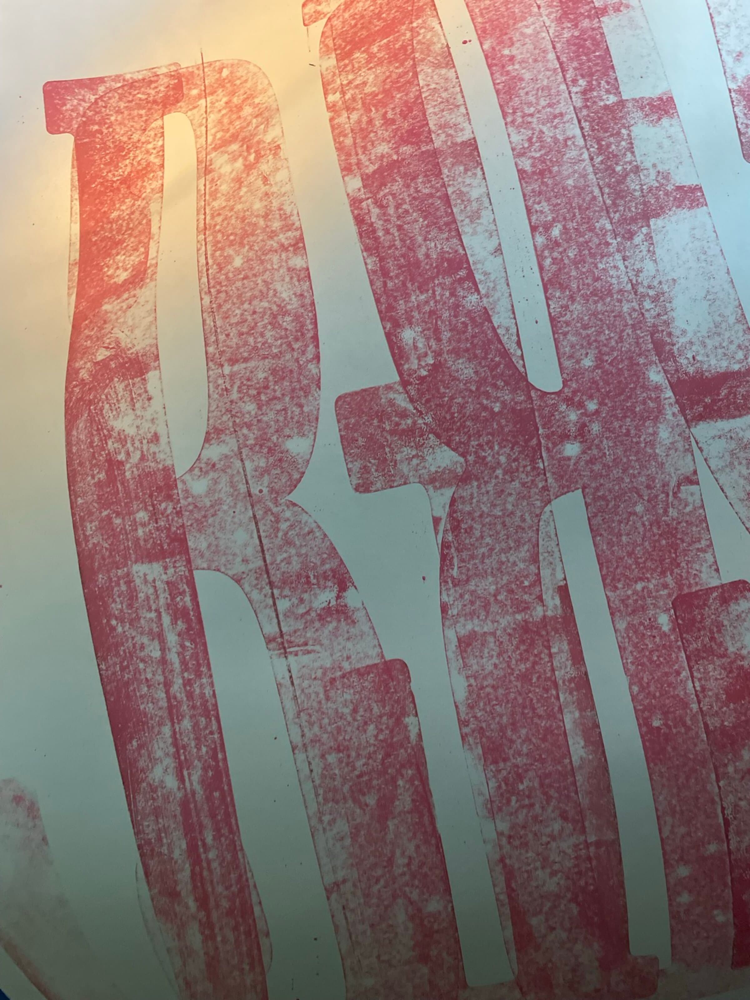 A macro abstract close-up of the same giant pull: pink ink against white paper, the letterforms cropped so only the curves and counters are visible as abstract shapes. The hand-pressed irregularities give the surface a sponged, weathered texture.