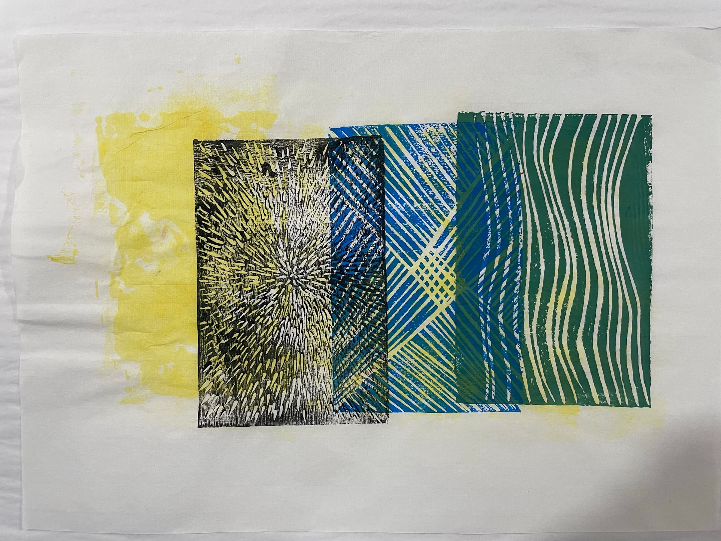 A four-block print in cooler tones: a yellow ground wash on the left, a black dot-burst block, a blue radial-burst block, and a green wave-line block.