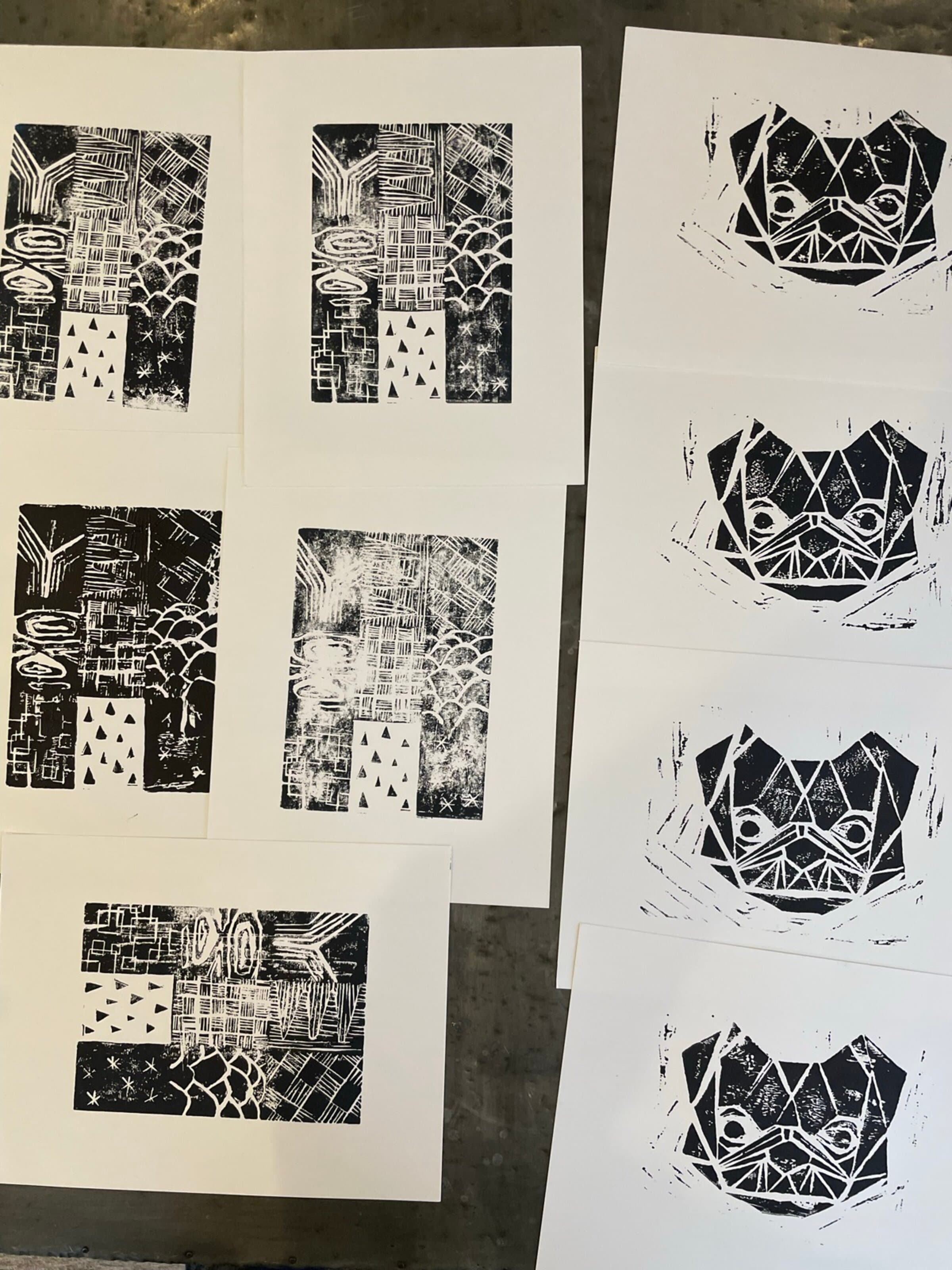 A larger flat-lay on a concrete-grey surface: a top row of four bulldog face prints in dark navy halftone, and a bottom group of five texture-grid pulls also in dark navy. The full studio output of the session shown together: same ink, same paper stock, two different blocks.
