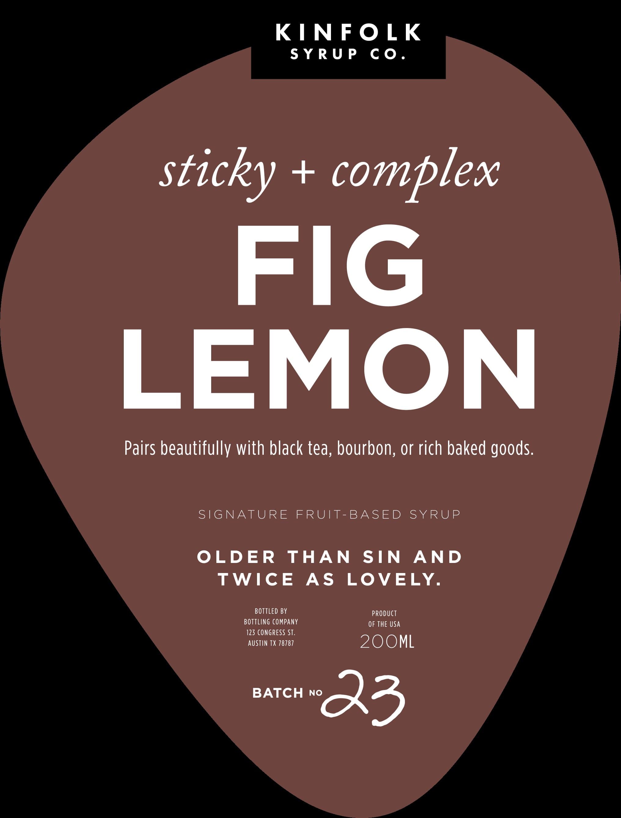 The Fig Lemon label: deep fig-brown teardrop, KINFOLK SYRUP CO. on a small black tag at the top, 'sticky + complex' italic kicker, FIG LEMON in chunky white display caps stacked, 'Pairs beautifully with black tea, bourbon, or rich baked goods,' and 'Older than sin and twice as lovely' as the personality line. BATCH NO 23 in handwritten script at the bottom.