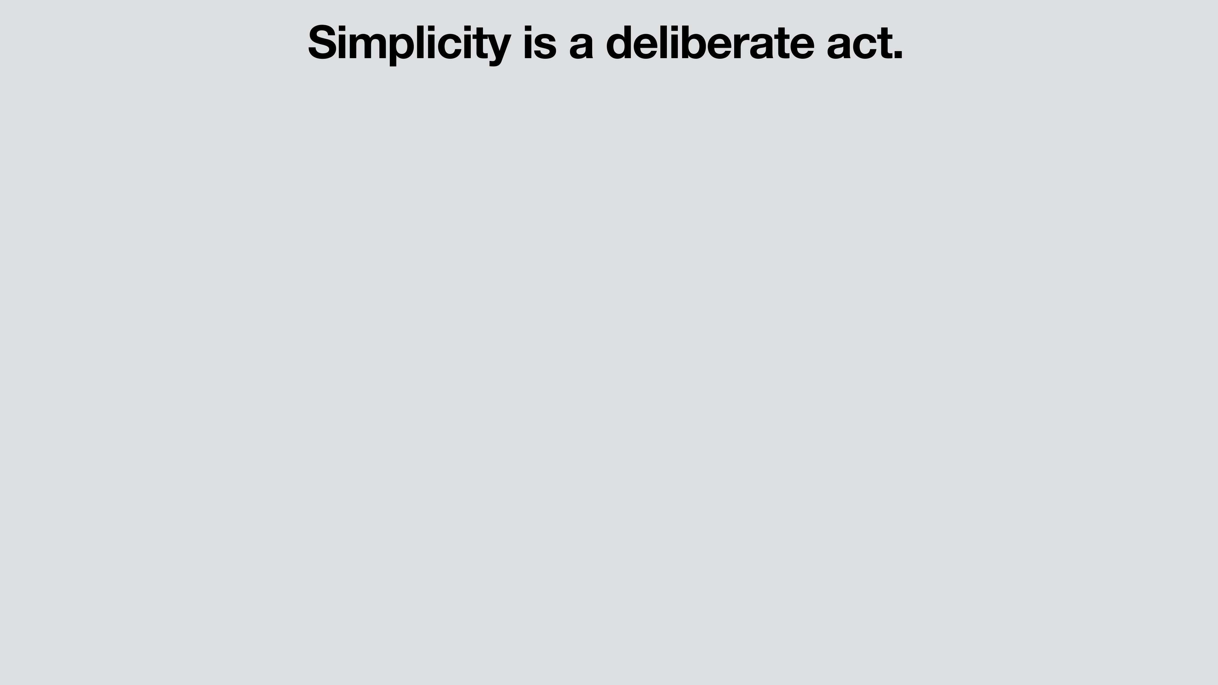 A presentation slide on a light gray ground with a single line of bold black sans-serif text near the top: 'Simplicity is a deliberate act.'